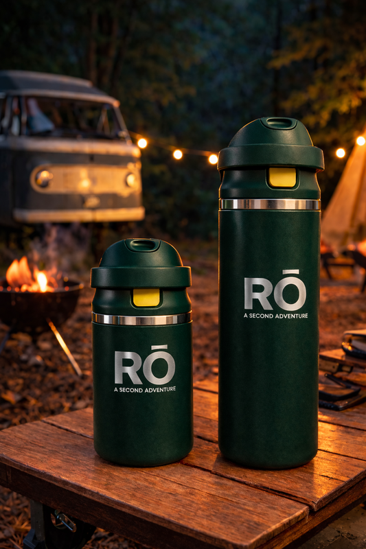 Two green water bottles with 'RO' branding on a wooden table outdoors.