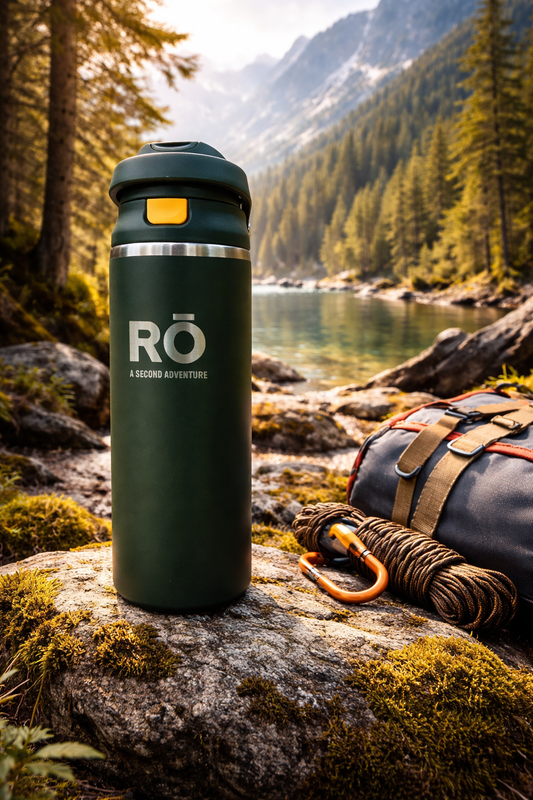 Green RO tumbler on a rock with a scenic mountain and lake background